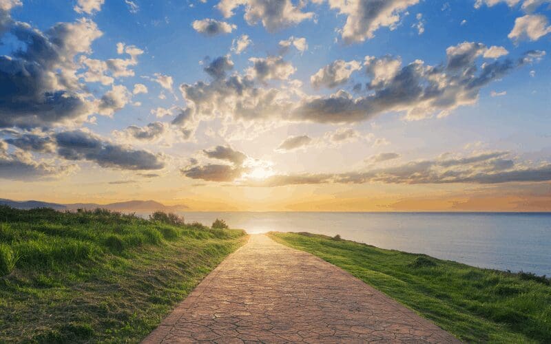 A picture of a path with a sunset over top it.