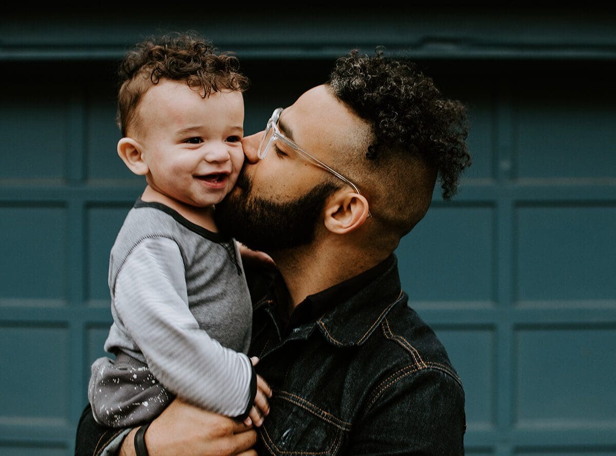 A parent holding their toddler child. Conscious parenting help with better family relationships.