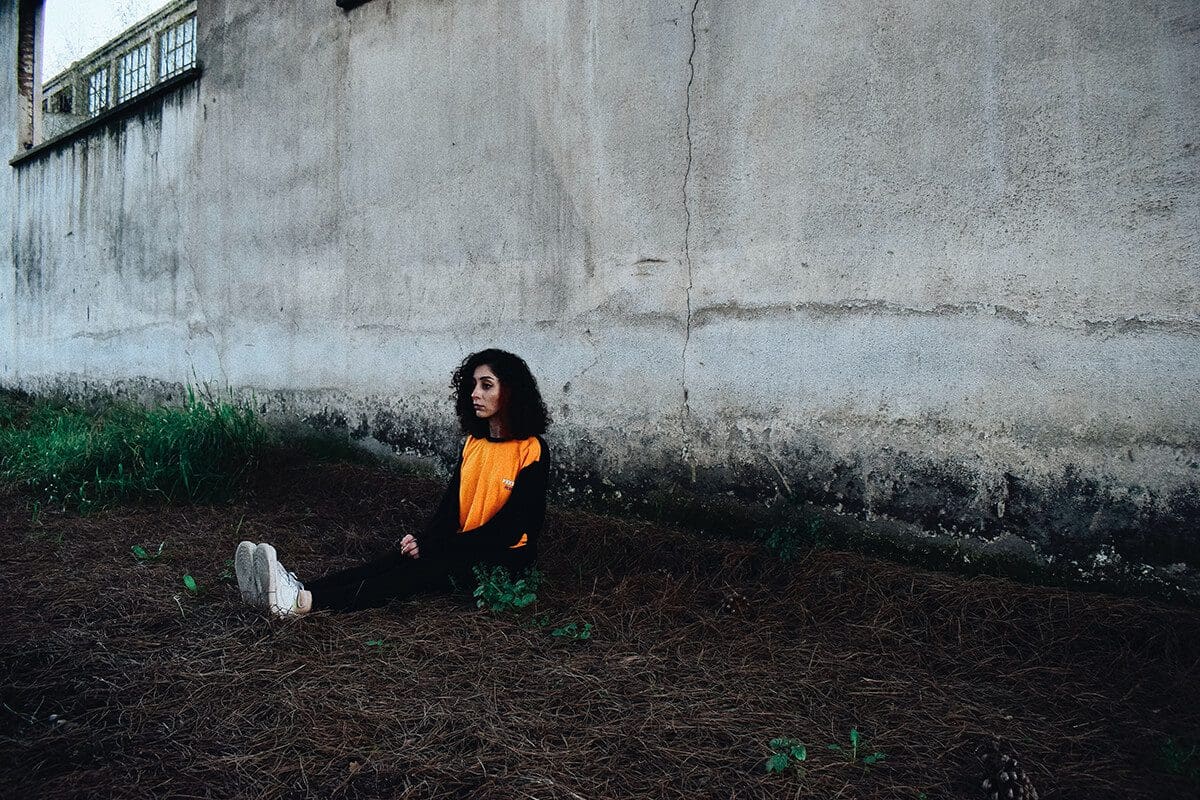 Woman sitting on the ground, contemplating her loss..