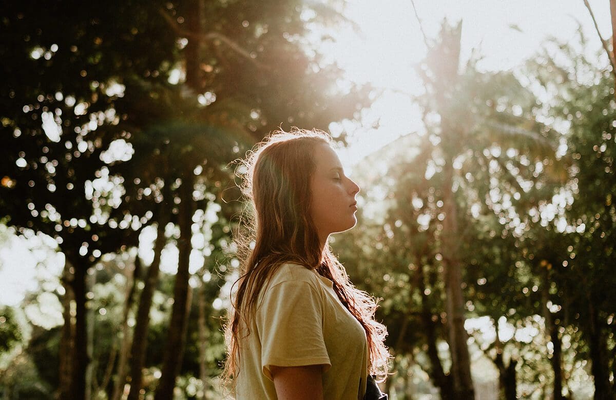 Woman in nature, with her eyes closed, focusing her mind on connecting with her intuition.