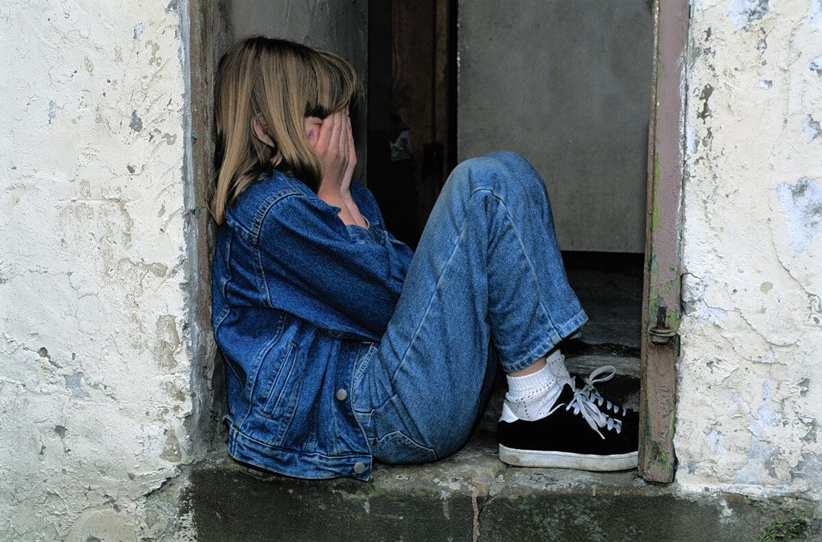 Father's day can be complicated - image of a young girl sadly hiding her face in her hands.